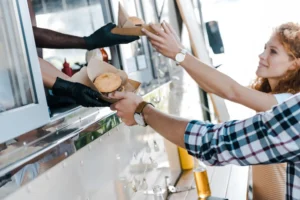 Street food vendor passing burger to customer