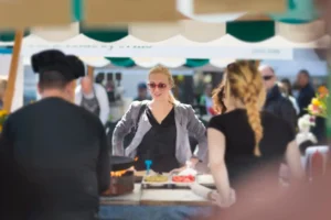 two workers behind food stand with customer infront ordering