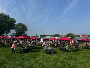large scale public event with catering trucks arranged in food village with picnic benches